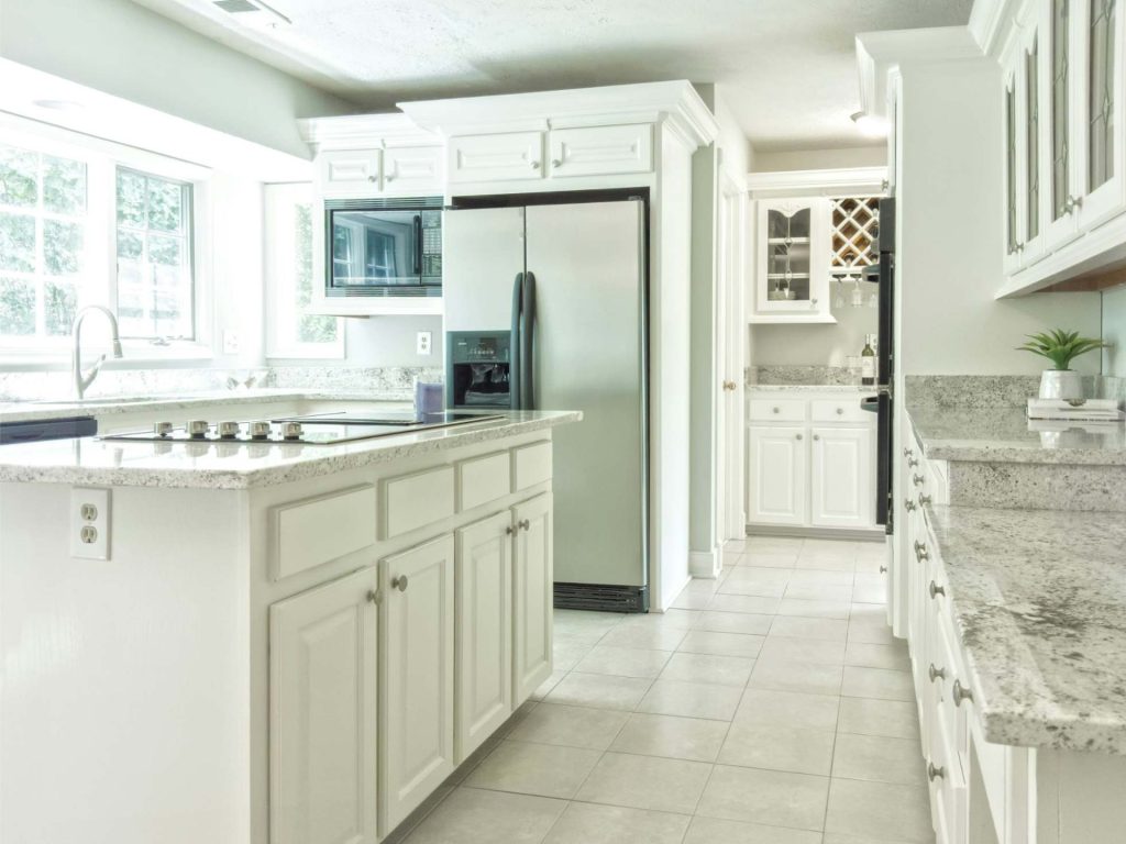  Bright, modern kitchen with granite countertops and white cabinets.