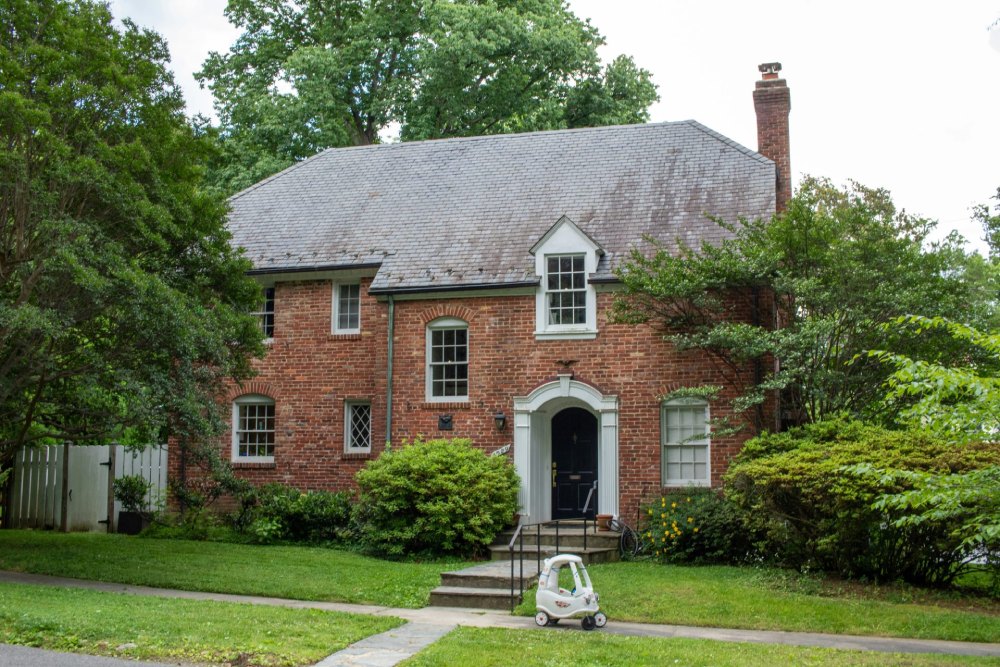 Classic brick house surrounded by lush green landscape.